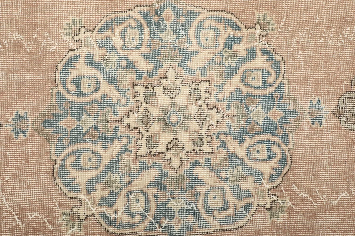 Close-up of the intricate blue medallion design and faded wool pile