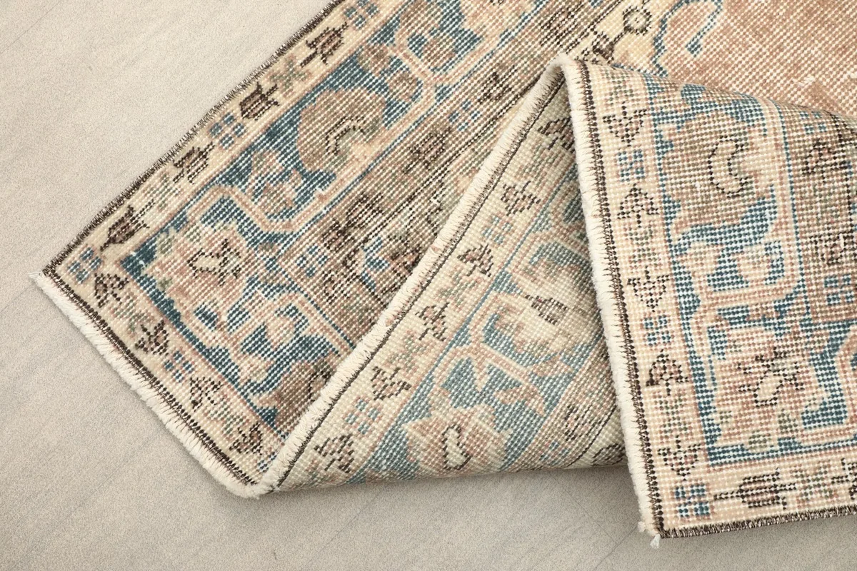 View of the vintage rug folded to show the hand-knotted construction and back