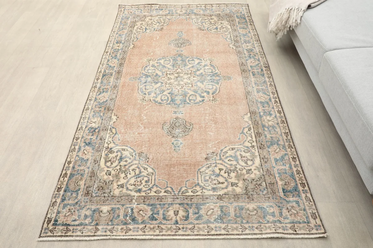 Overhead view of the rose and blue vintage rug in a neutral room setting