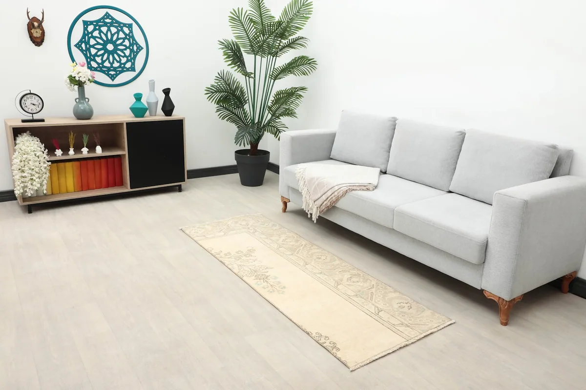 Cream and gray vintage runner rug displayed in a living room setting next to a gray sofa.