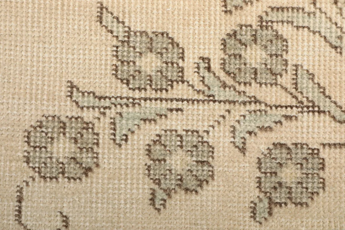 Macro view of the hand-knotted wool pile, revealing the intricate floral pattern and texture.