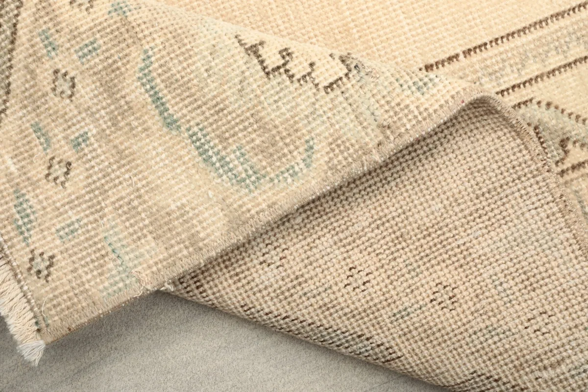 Folded view of the rug's back, detailing the woven structure and areas of subtle color variation.
