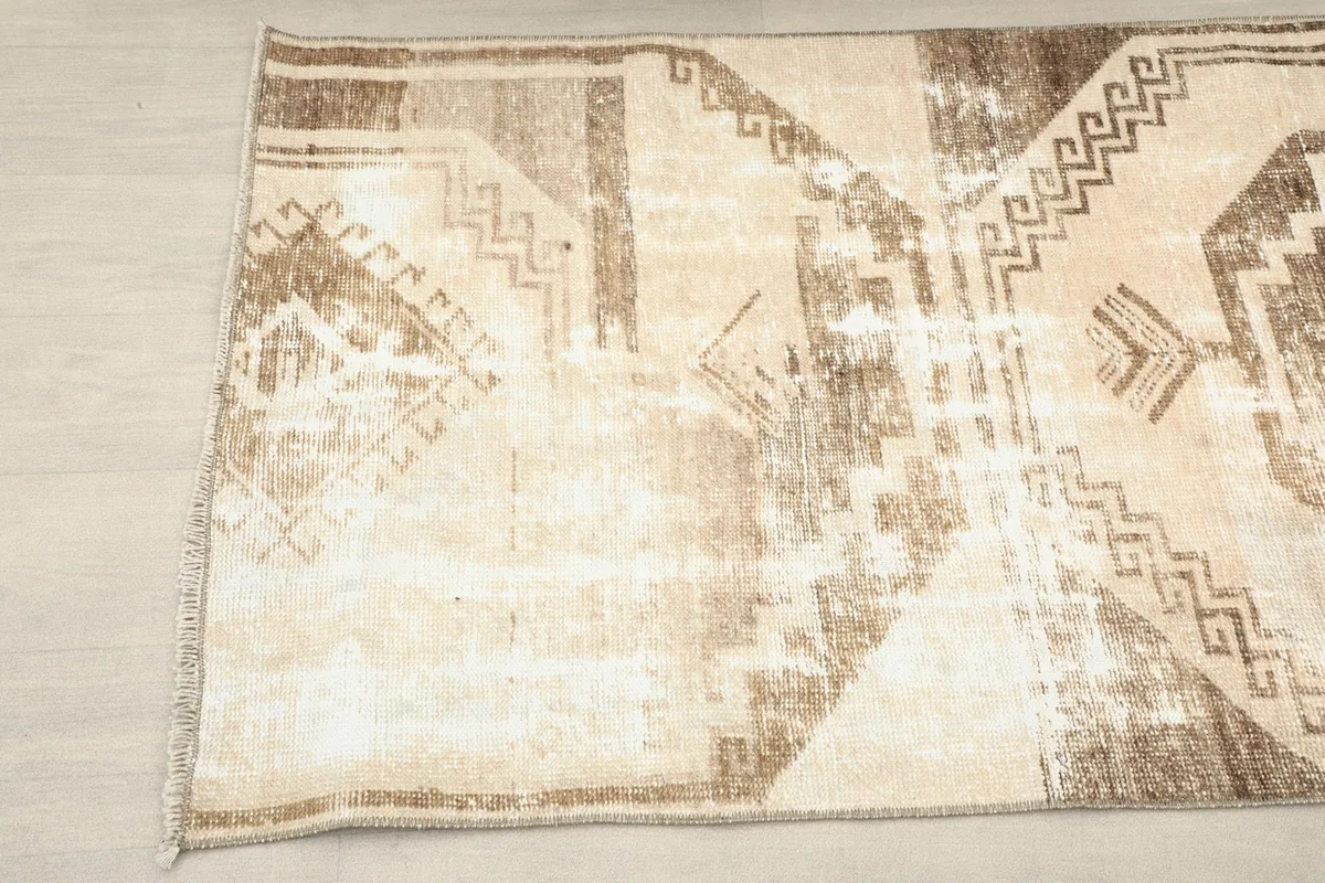 Close-up detail of the rug's central brown geometric motif and surrounding beige areas.