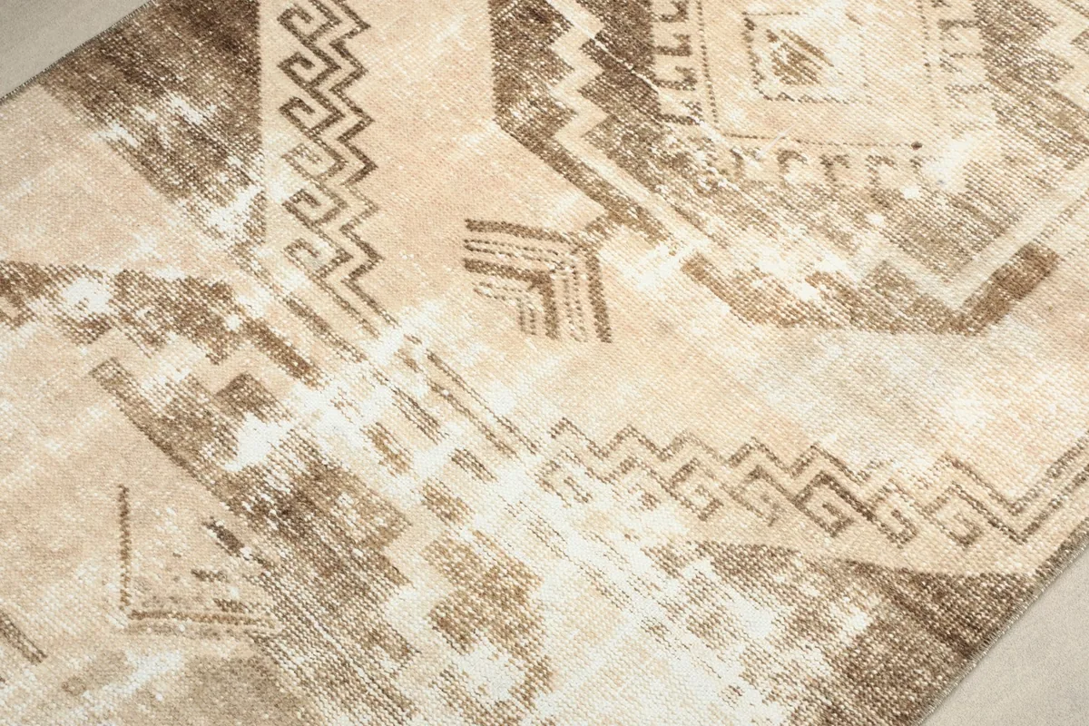 Detailed view of the intricate brown geometric patterns and the distressed texture of the pile.