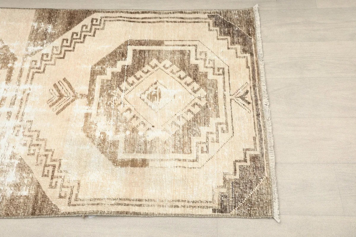 Overhead view of the rug showcasing its beige field with brown geometric and tribal patterns.