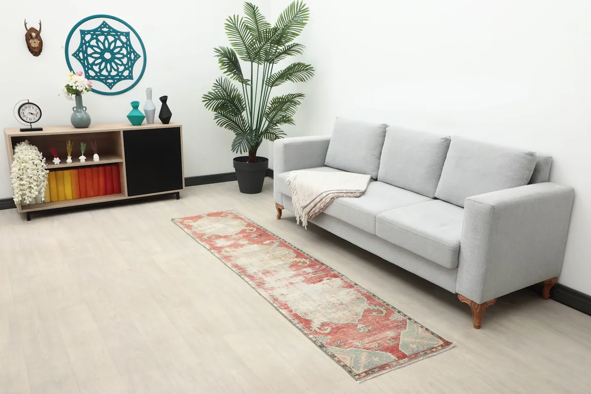 Vintage red and ivory runner rug laid out in a modern living room setting next to a gray sofa.