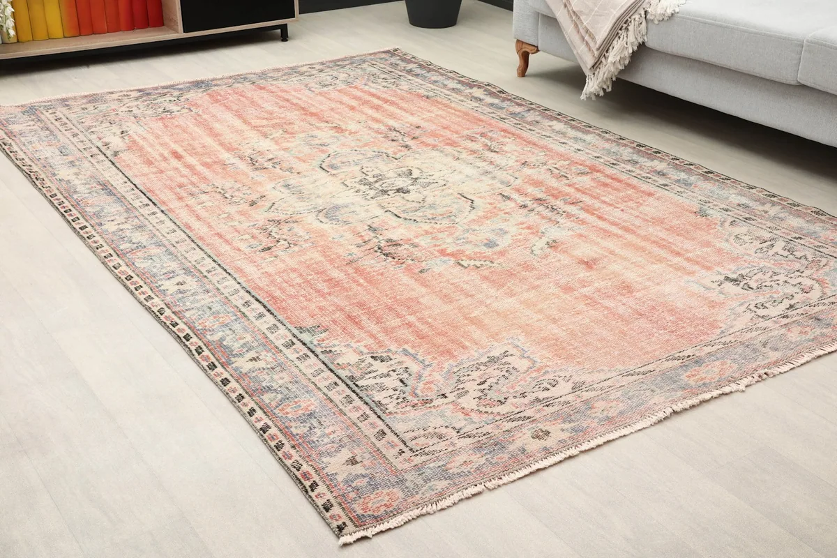 Close-up angled view of the Anatolian rug, showing the central medallion and faded rose tones