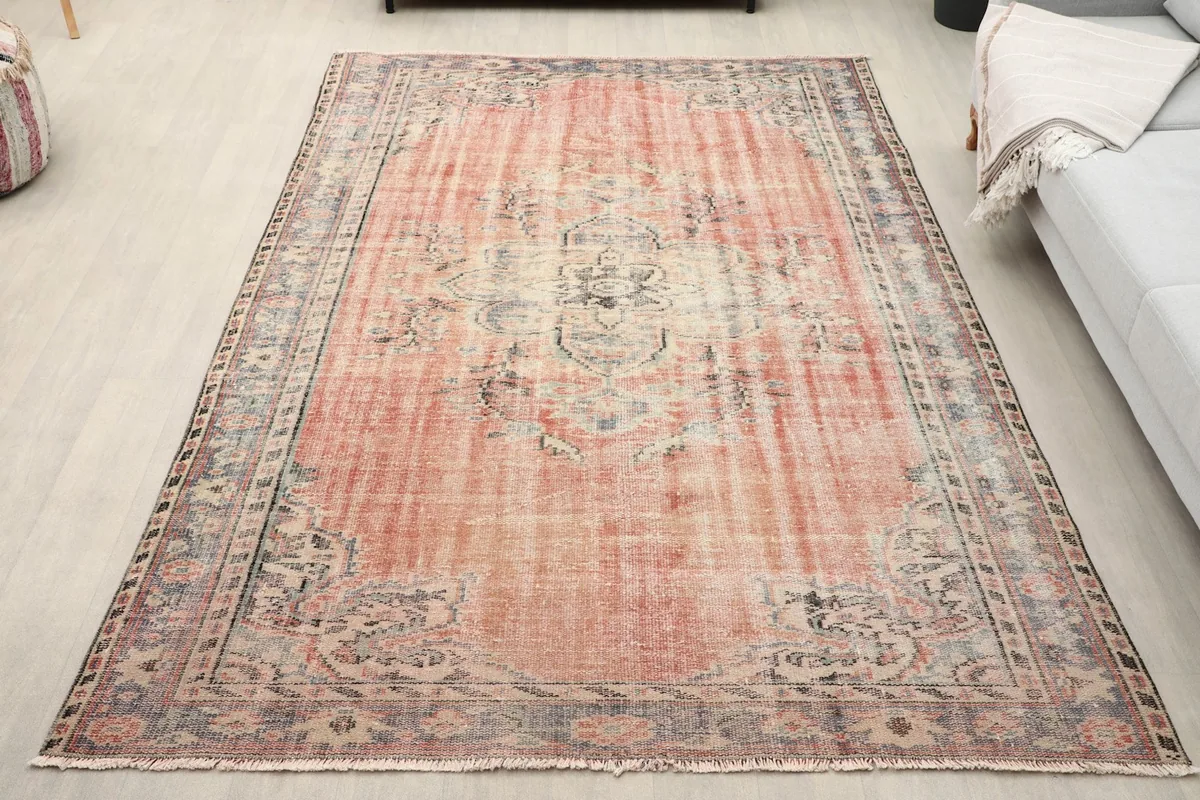 Vintage rose and gray Anatolian rug displayed in a living room setting with a light gray sofa