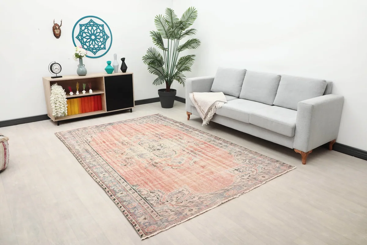 Wide shot of the rose and gray vintage rug in a modern living space with a plant and console