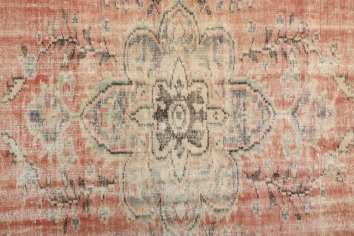 Close-up of the central medallion design, showing gray, cream, and blue details on a rose field