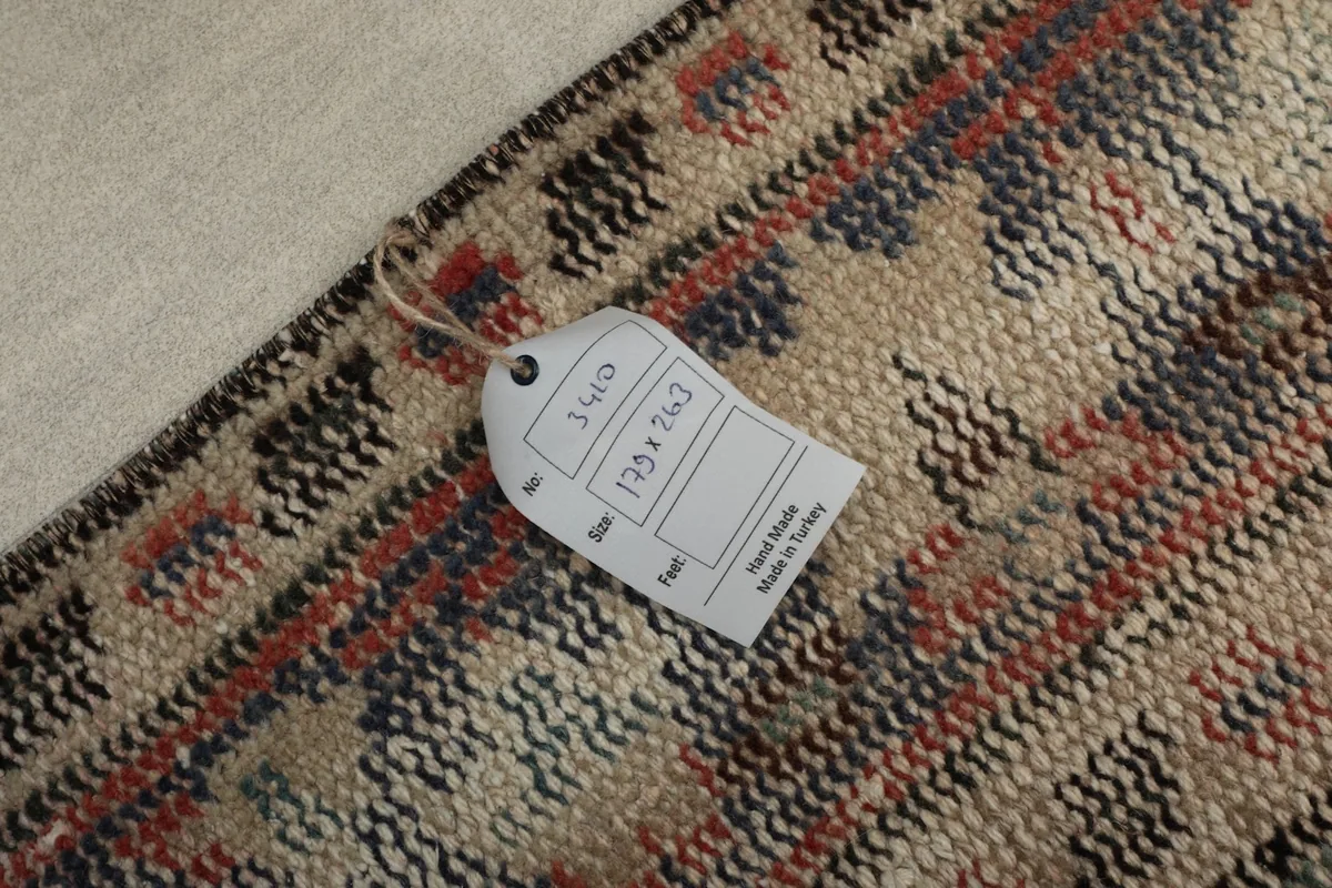 Close-up of the rug's back with a tag, showing the tight hand-knotting on a cotton foundation