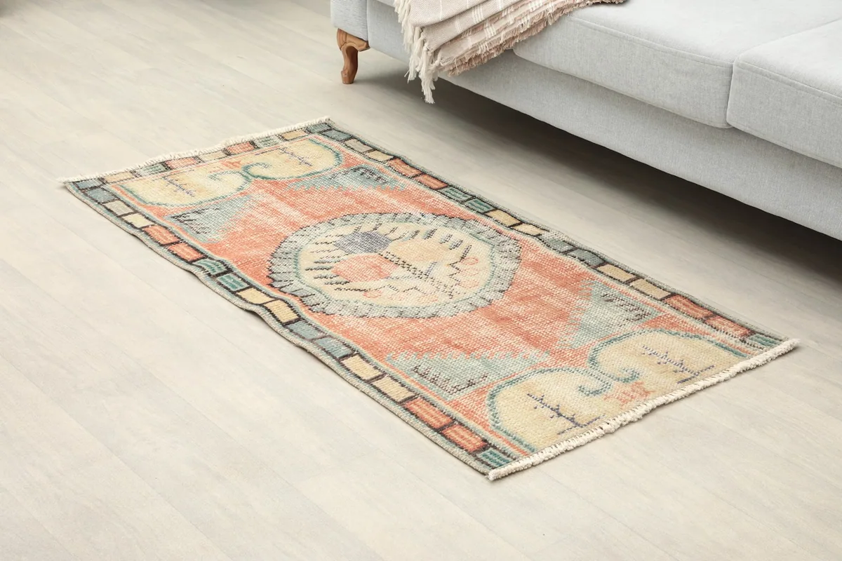 Angled view of the rug showing its placement on a light wood floor next to a sofa