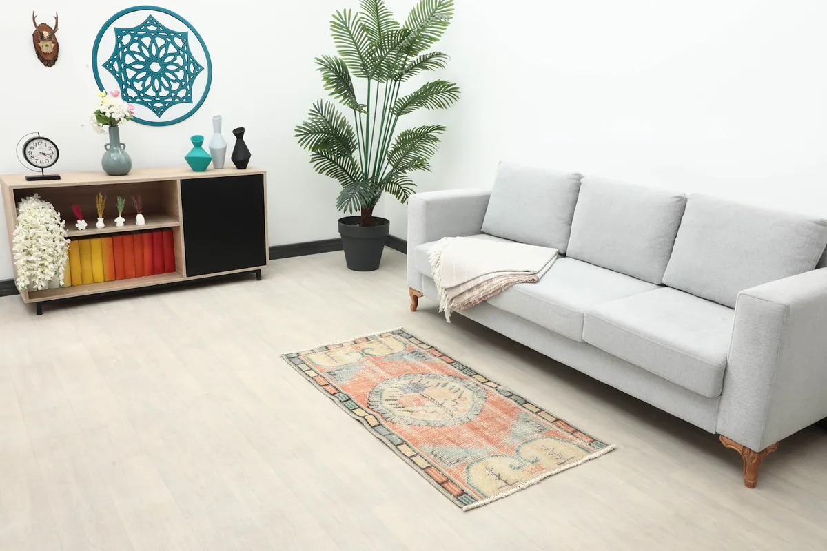 Vintage Anatolian rug placed in a living room setting next to a sofa and cabinet