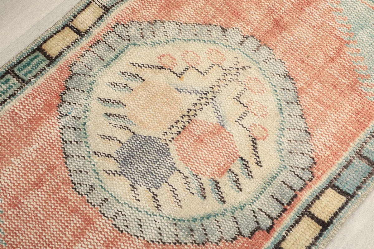 Detailed view of the central medallion-like motif in beige, light blue, and rust tones