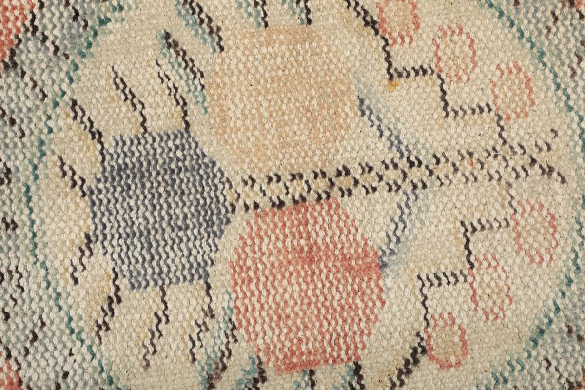 Extreme close-up of the low wool pile and hand-knotted texture of the rug