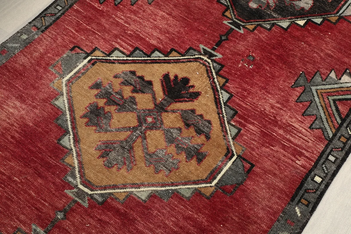 Detailed view of the middle tan and gray geometric motif on the red field.