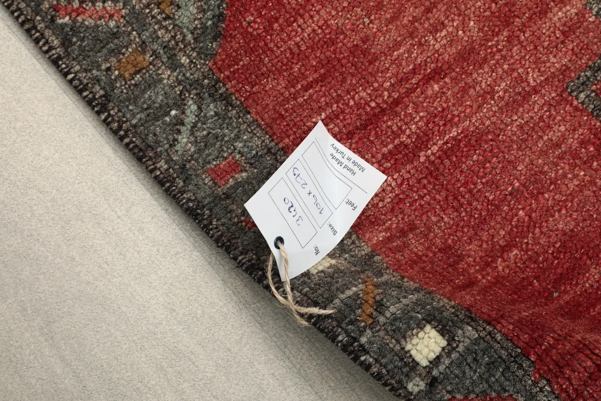 Close-up of the rug's back with a tag, showing the hand-knotted cotton foundation.