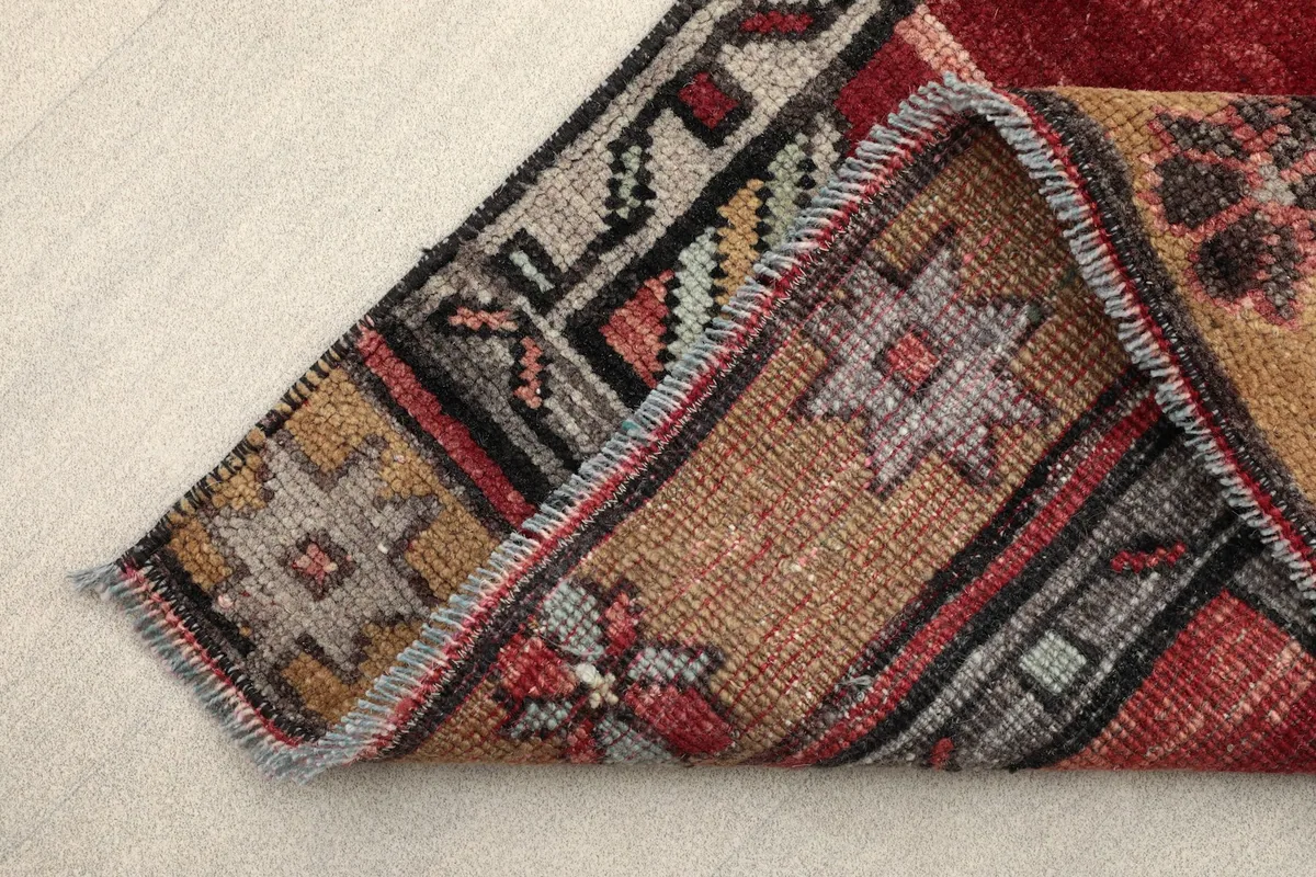Close-up of a corner folded back, showing the back of the rug and fringe details.