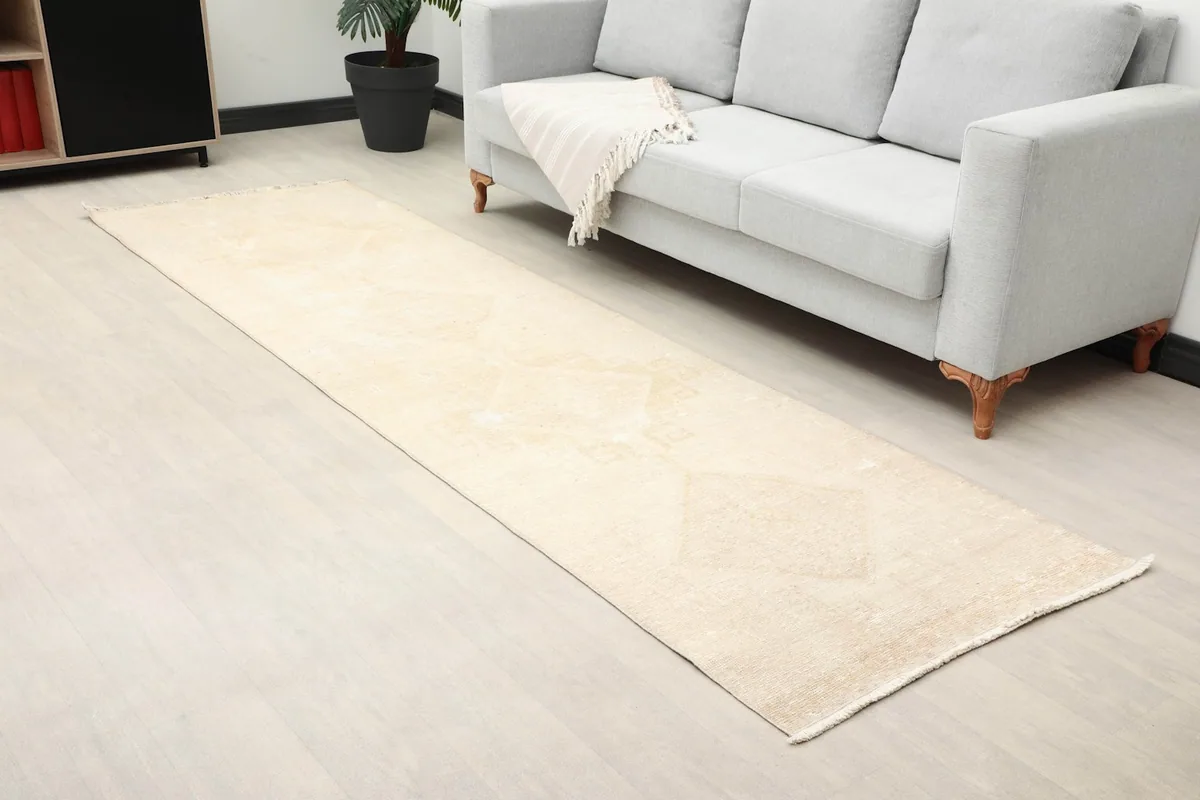 Long view of the ivory runner rug in a room with a sofa and minimalist furniture, showing its scale