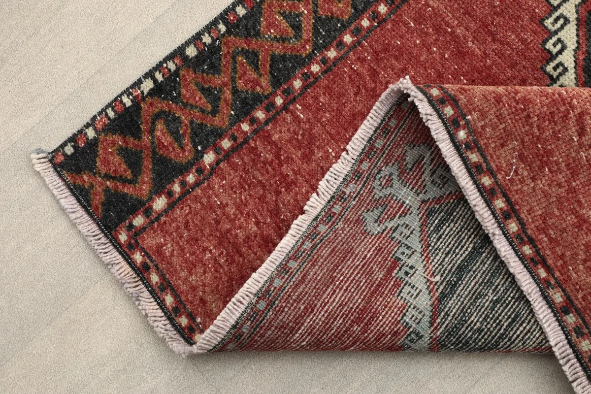 Folded corner of the rug revealing the cotton foundation and fringe