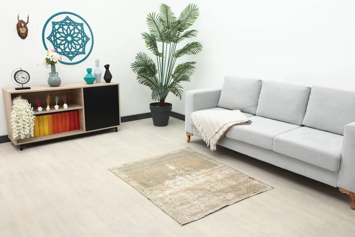 Small green and beige vintage rug in a modern living room setting with a gray sofa