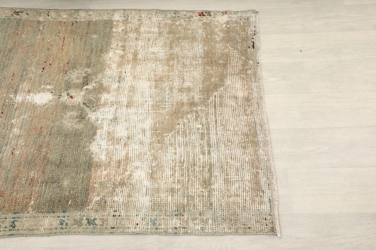 Close-up view of the rug's surface, showing the faded beige and green tones