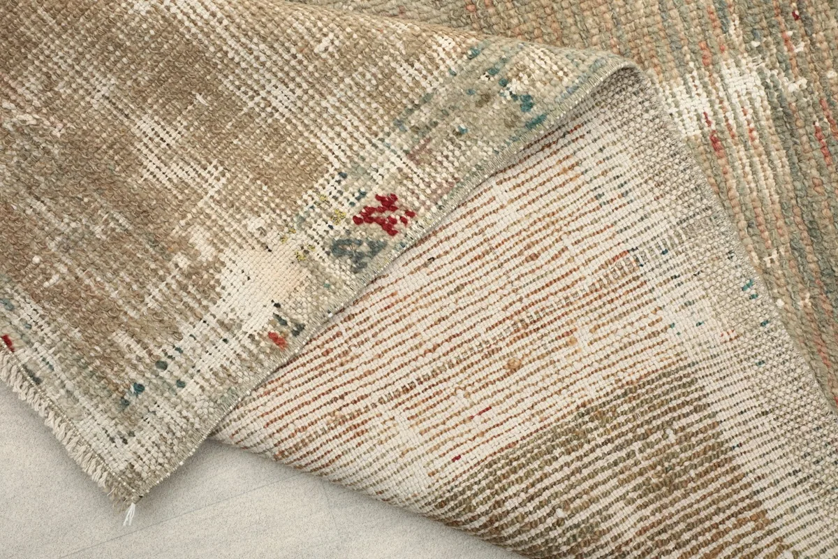View of the rug's reverse side and folded edge, revealing the cotton foundation