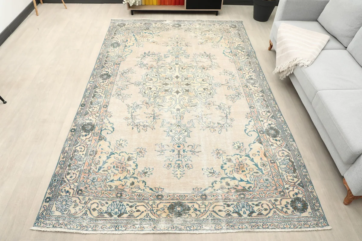 Full overhead view of the beige vintage Anatolian rug with blue and rose floral motifs.