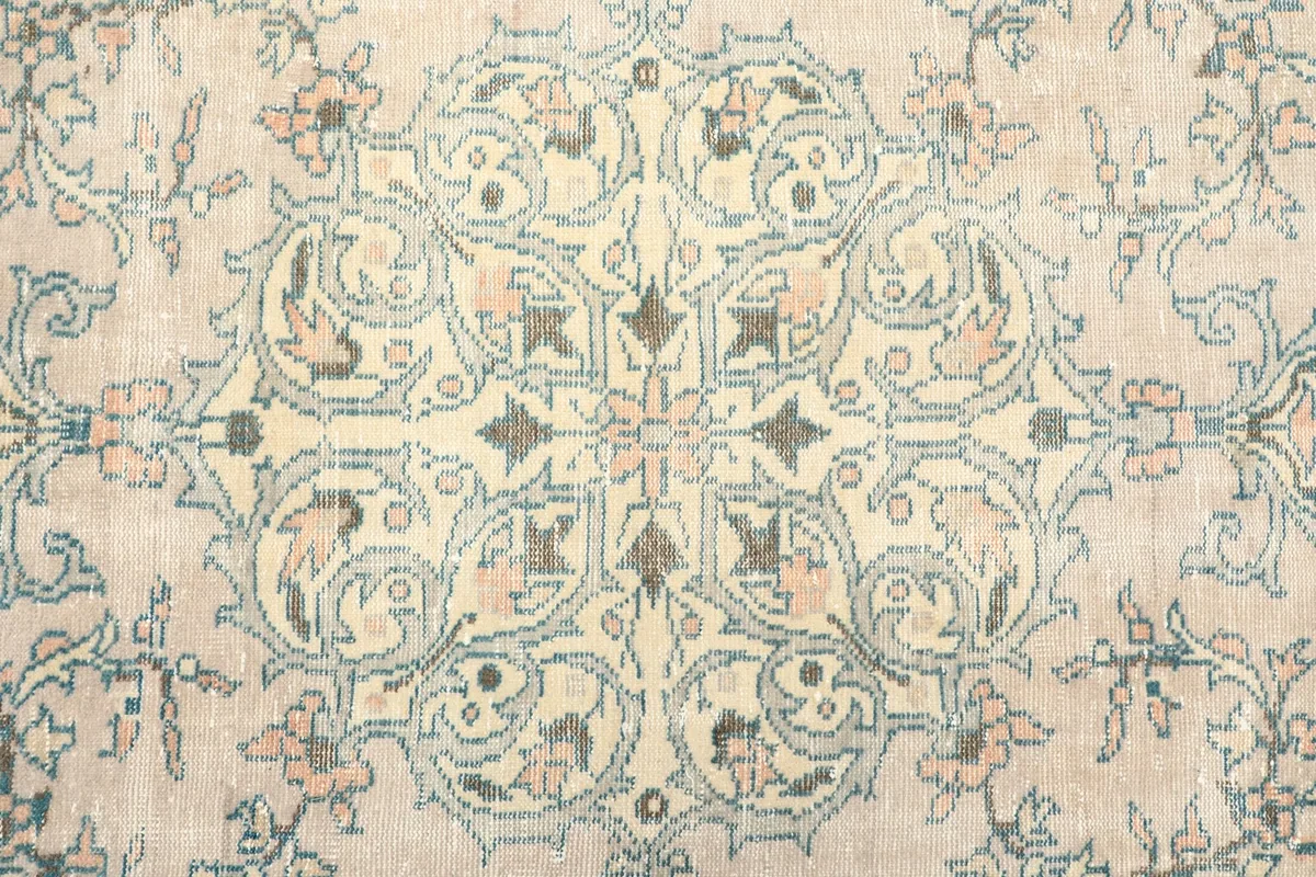 Close-up of the central medallion design, highlighting the beige, blue, and rose colors.