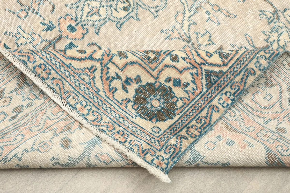 Folded corner of the rug revealing the cotton foundation and reverse side of the knotting.