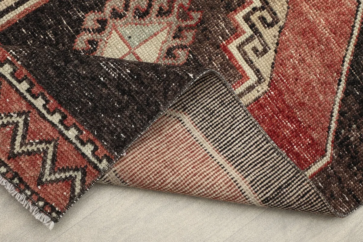 Folded corner of the rug, displaying the back of the rug and the woven foundation.