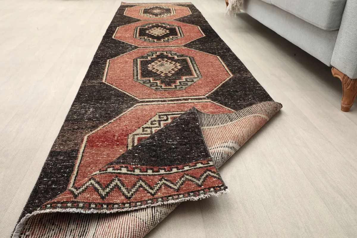 Runner rug with one end folded back, showing the thickness and construction of the vintage piece.