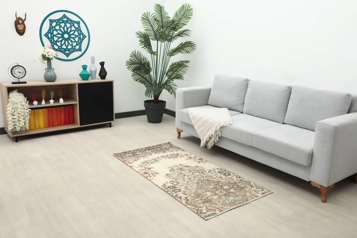 Vintage Anatolian rug displayed in a living room setting next to a gray sofa and wooden cabinet