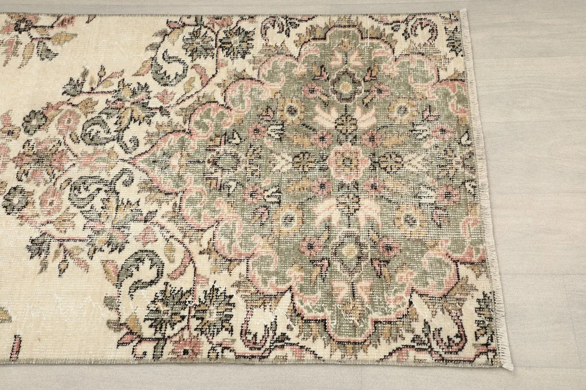 Close-up detail of the central floral medallion with green, rose, and beige tones