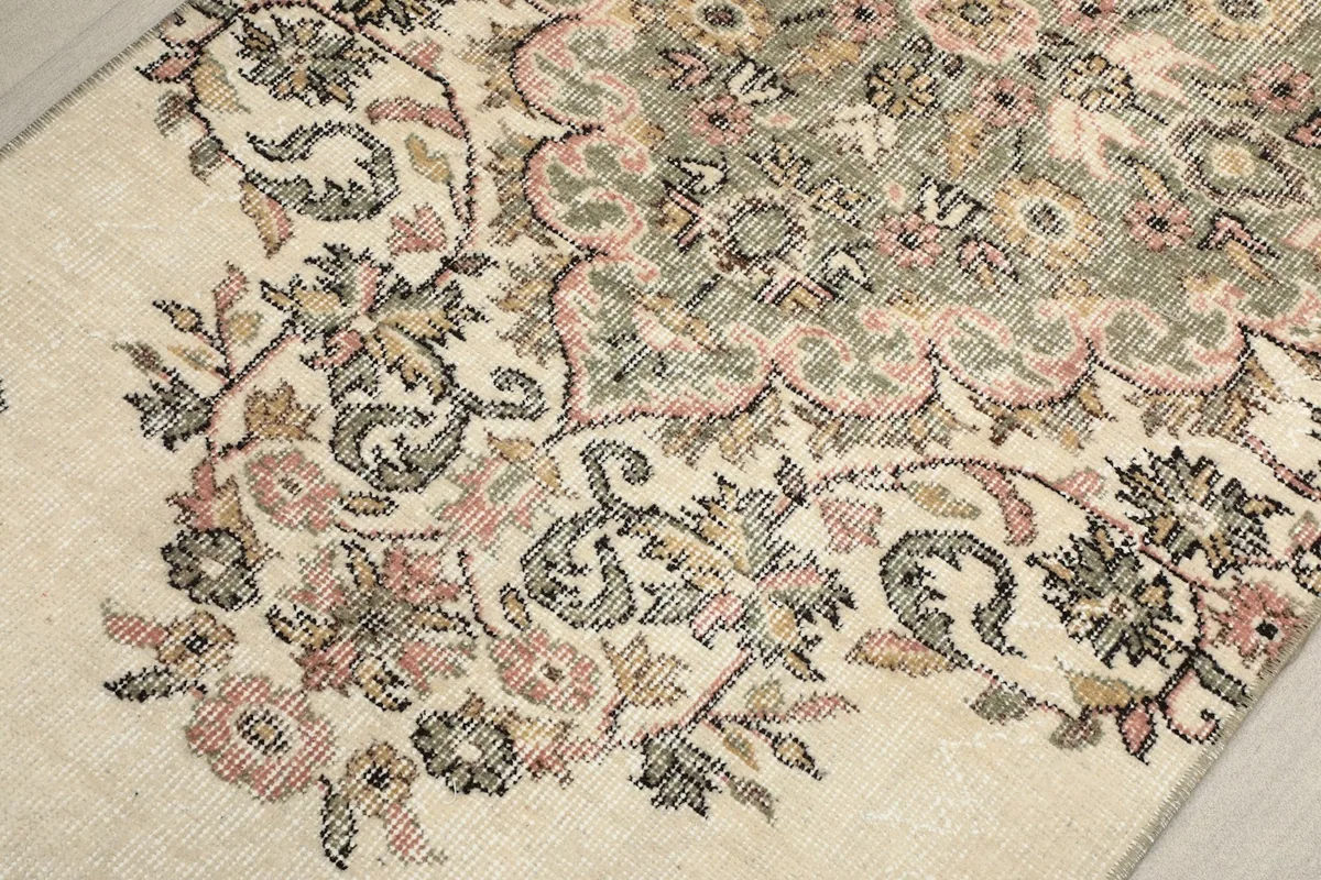 Close-up of the intricate floral and botanical motifs in rose, green, and beige