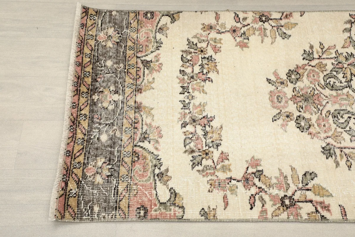 Detail of the rug's border showing black and rose floral elements on an ivory field