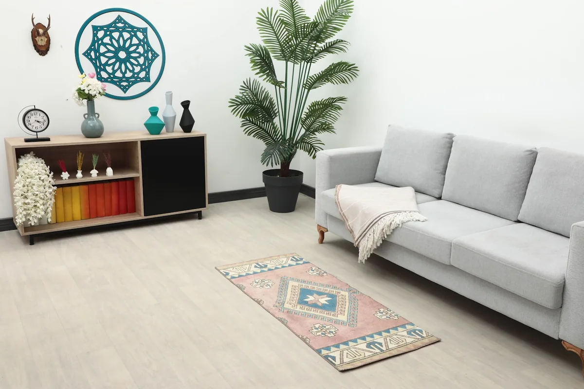 Full room view showing the rose and blue vintage rug placed in a living area with a couch and console.