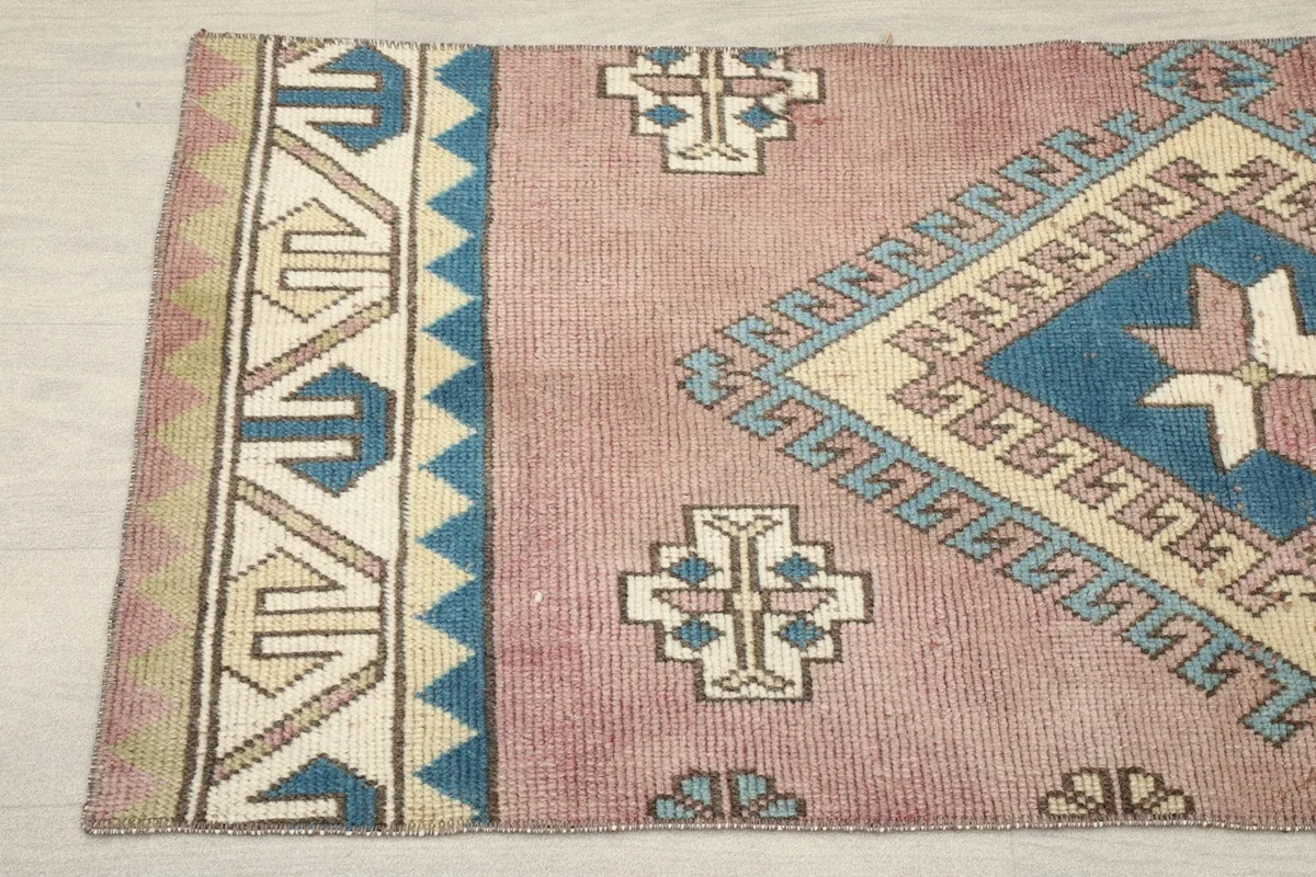 Close-up of the left border and field of the rose rug, detailing the tribal motifs.