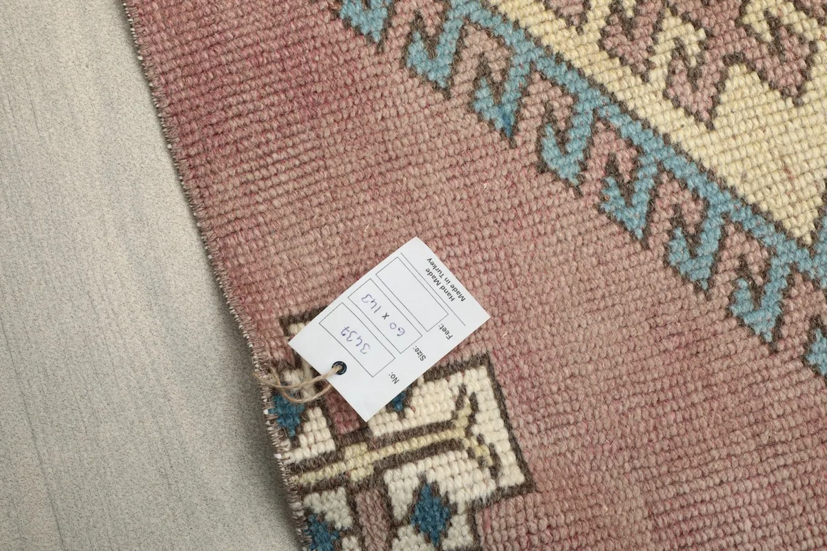Close-up of the rug's back with a tag, showing the hand-knotted cotton foundation.