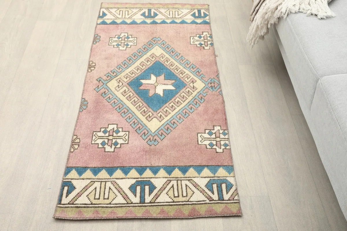 Overhead view of the rose and blue geometric rug on a light floor next to a couch.