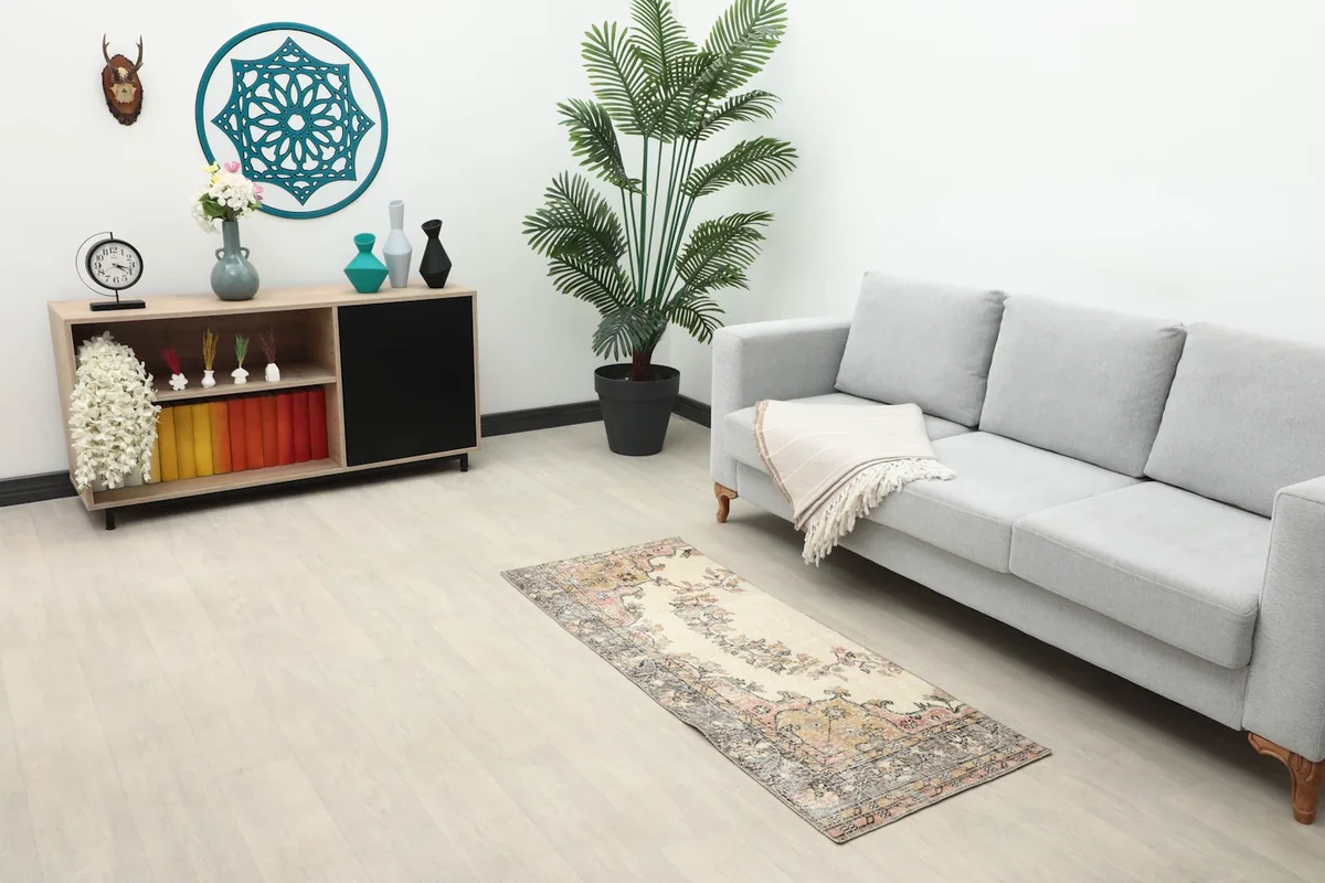 Vintage Anatolian runner placed in a modern living space with a gray sofa and light wood flooring.