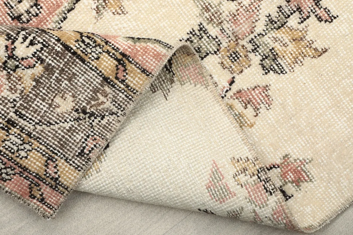 Underside of the rug, revealing the tightly woven cotton foundation and the back of the hand-knotted wool pile.
