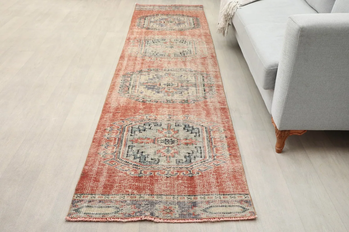 Runner rug placed in a room next to a light gray sofa, showing its length and scale.