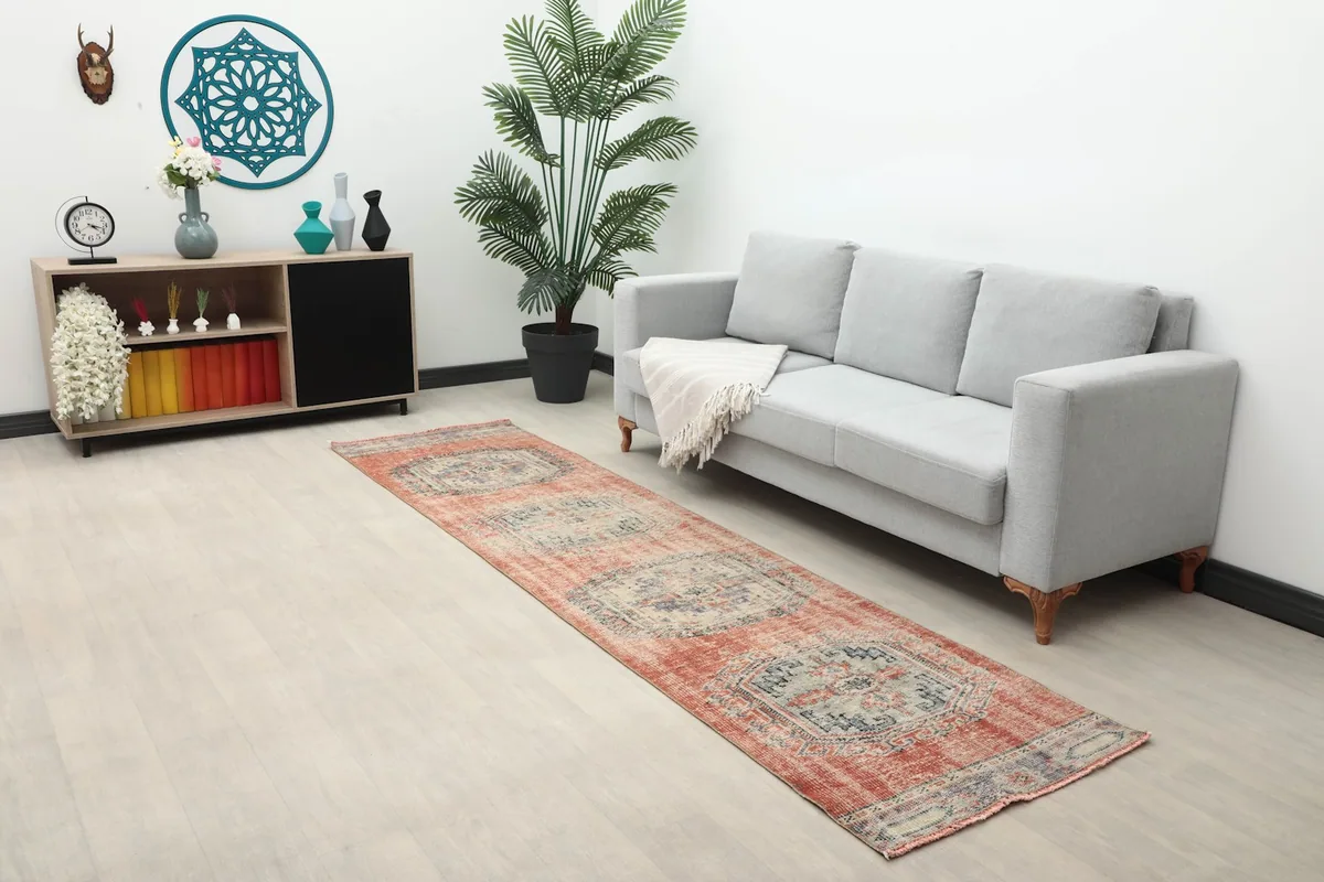 Full room view with the rust runner rug extending from a sofa towards a cabinet.