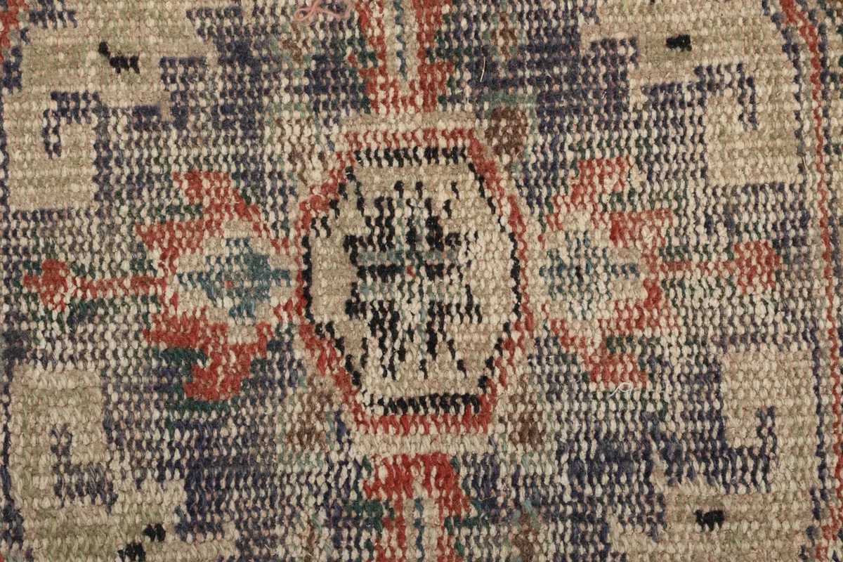 Extreme close-up showing the low wool pile and hand-knotted texture of the rug.