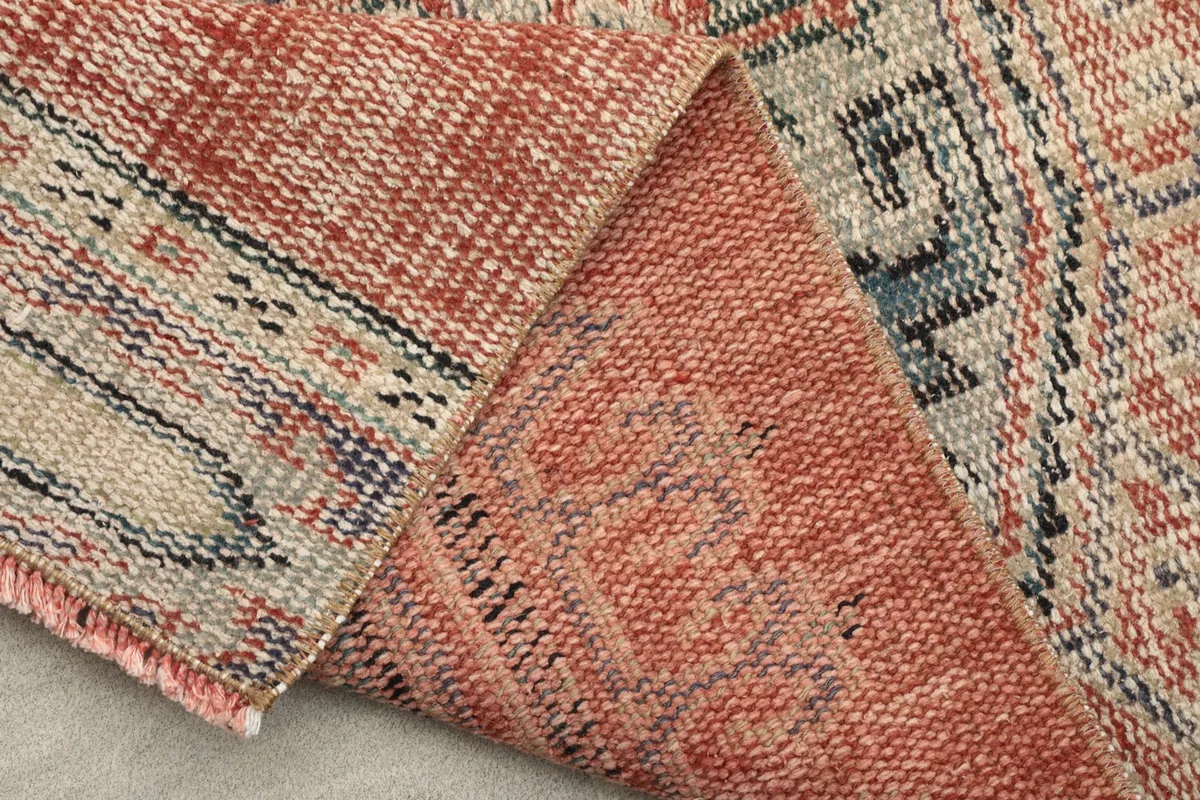 Folded rug showing the reverse side's weave and a glimpse of the front pattern.