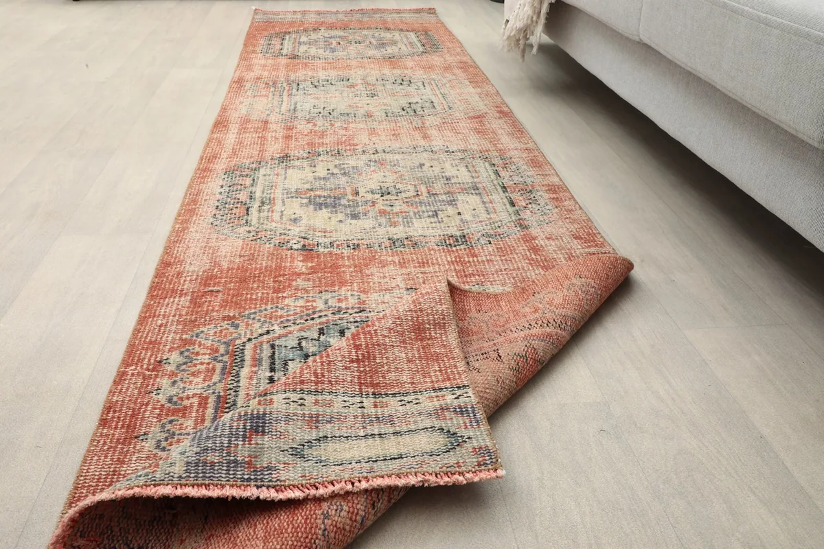 Runner rug partially unrolled on a light floor, demonstrating its flexibility and length.