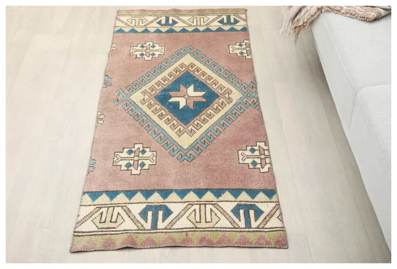 Full top view of the 1'11" x 4'7" rose and blue geometric vintage Anatolian area rug on a white background.