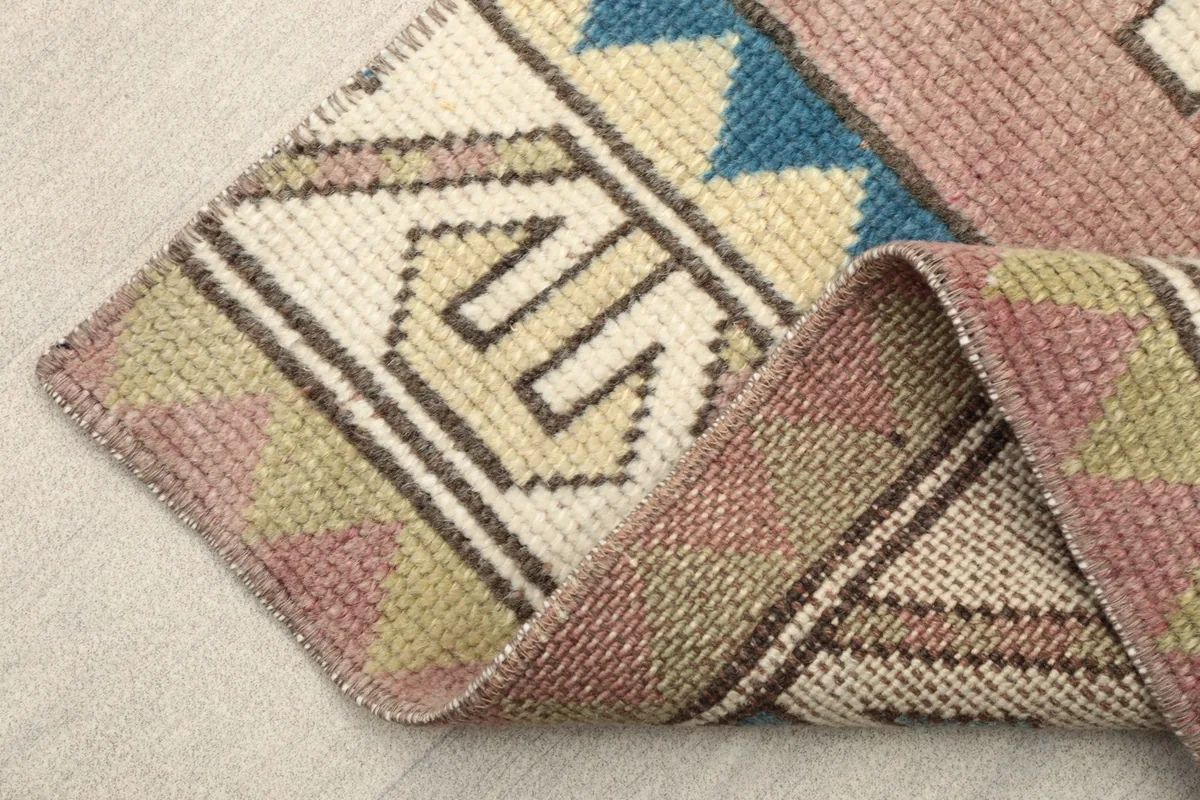 Folded edge of the rug, showing the low pile and the construction of the hand-knotted wool on cotton foundation.