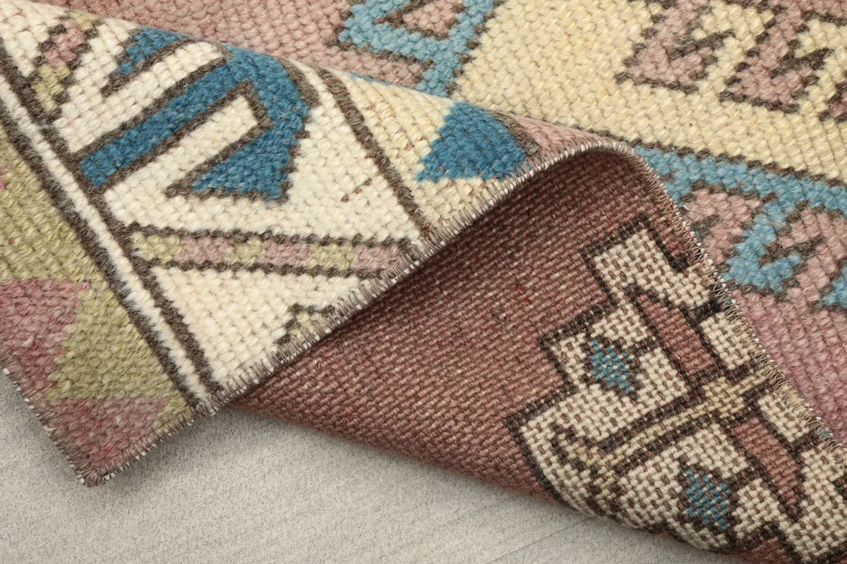 View of the back of the rug where it is folded, showing the tight knotting and cotton foundation.